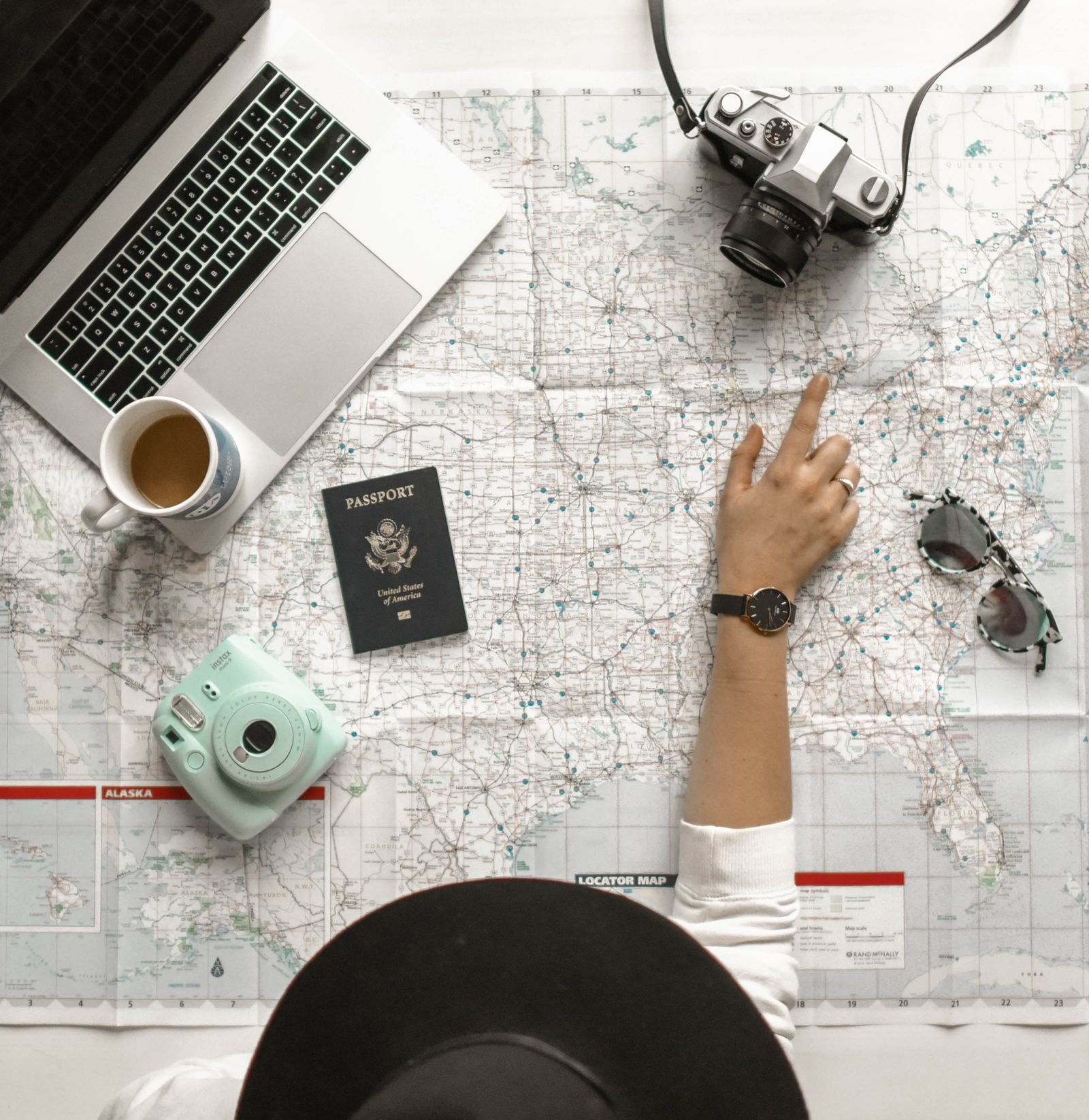 Mapa, pasaporte, cámara y portátil listos para planear y reservar un viaje